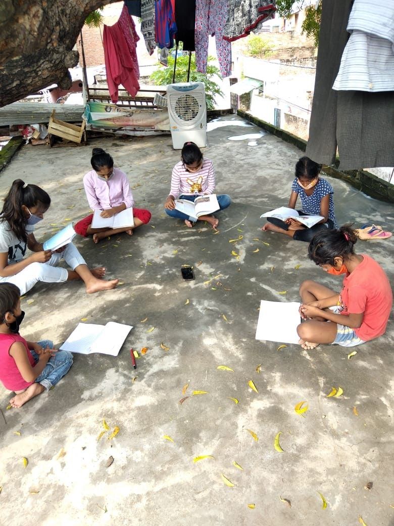 A group of children are sitting on the ground reading books.