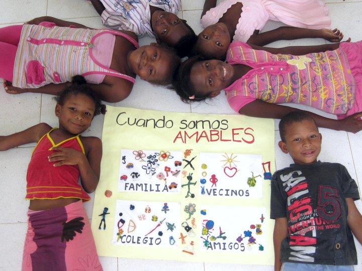 A group of children laying on the floor with a sign that says cuando somos amables