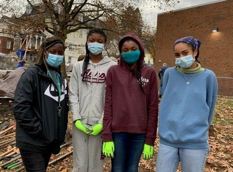 A group of young women wearing face masks and neon gloves are standing next to each other.