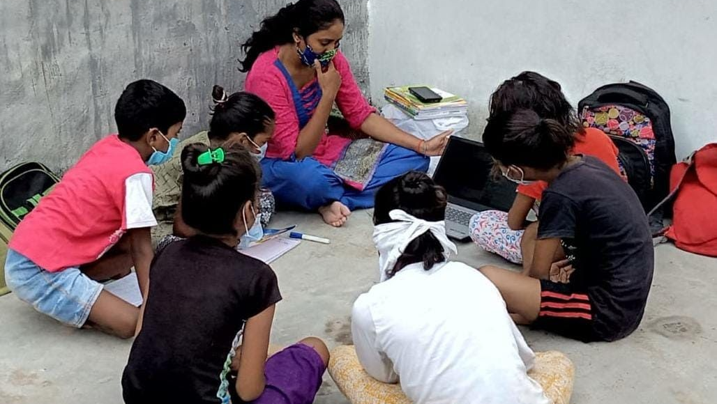 A group of children are sitting on the ground in a circle.