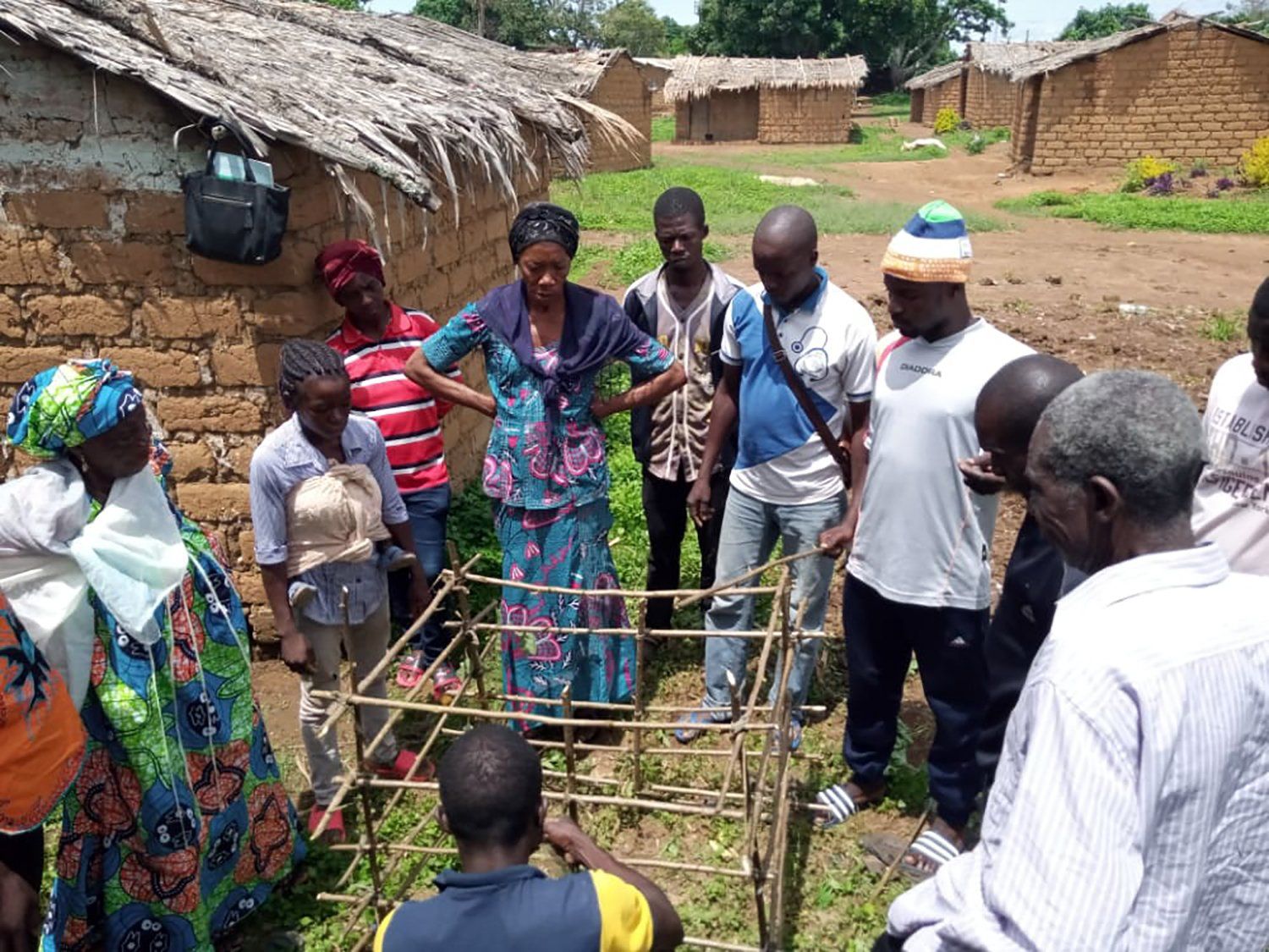 A group of people standing around a cage in a field