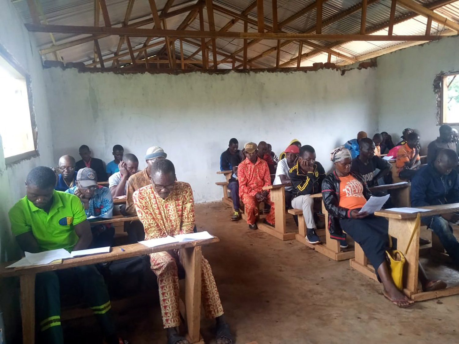 A group of people are sitting at desks in a classroom.
