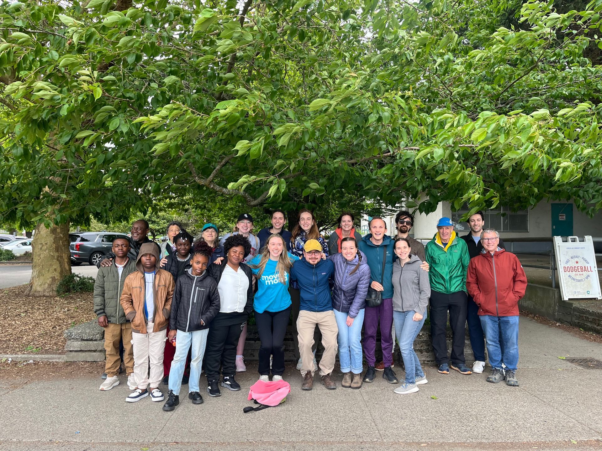 A group of people are posing for a picture under a tree.