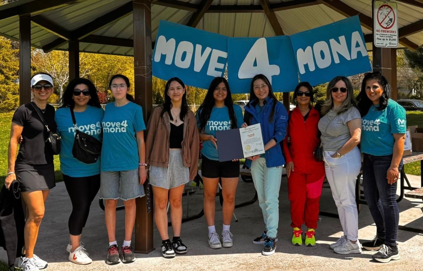 A group of women standing under a pavilion with a sign that says move 4 mona