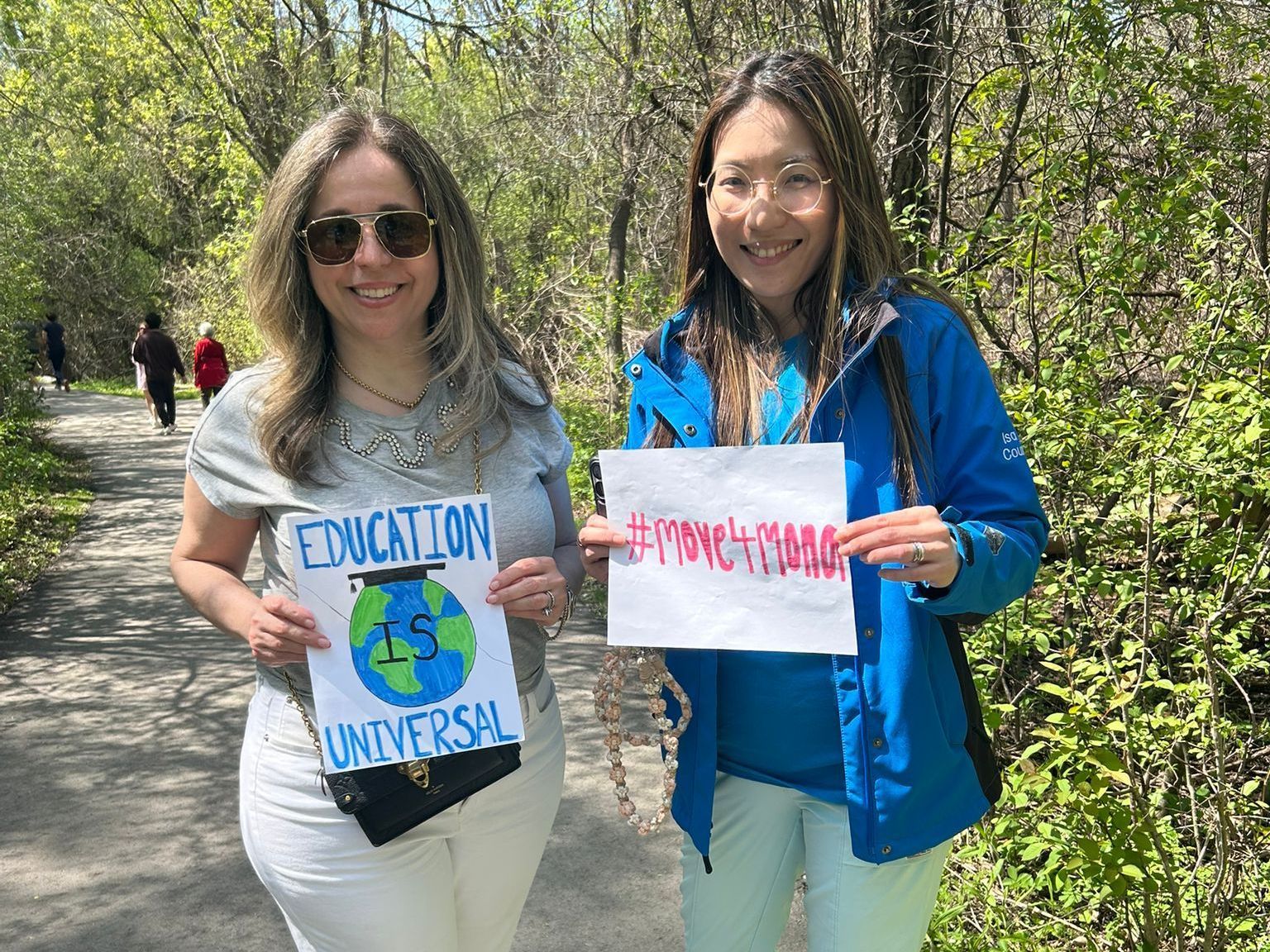 Two women are holding signs that say education is universal.
