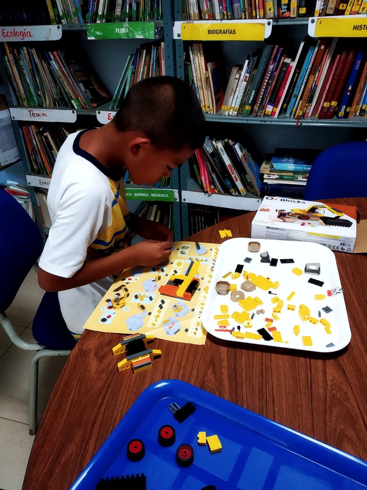 A boy is sitting at a table playing with lego blocks