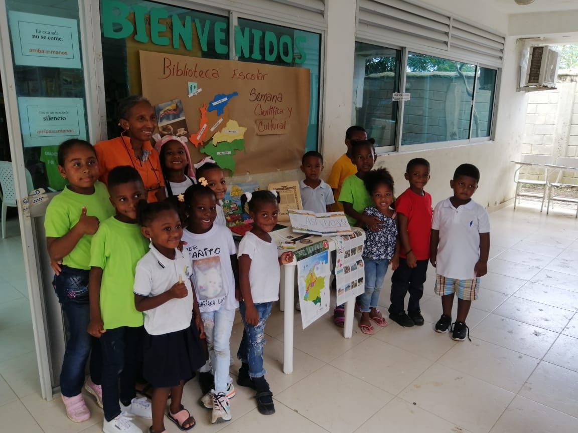 A group of children are posing for a picture in front of a sign that says bienvenidos.