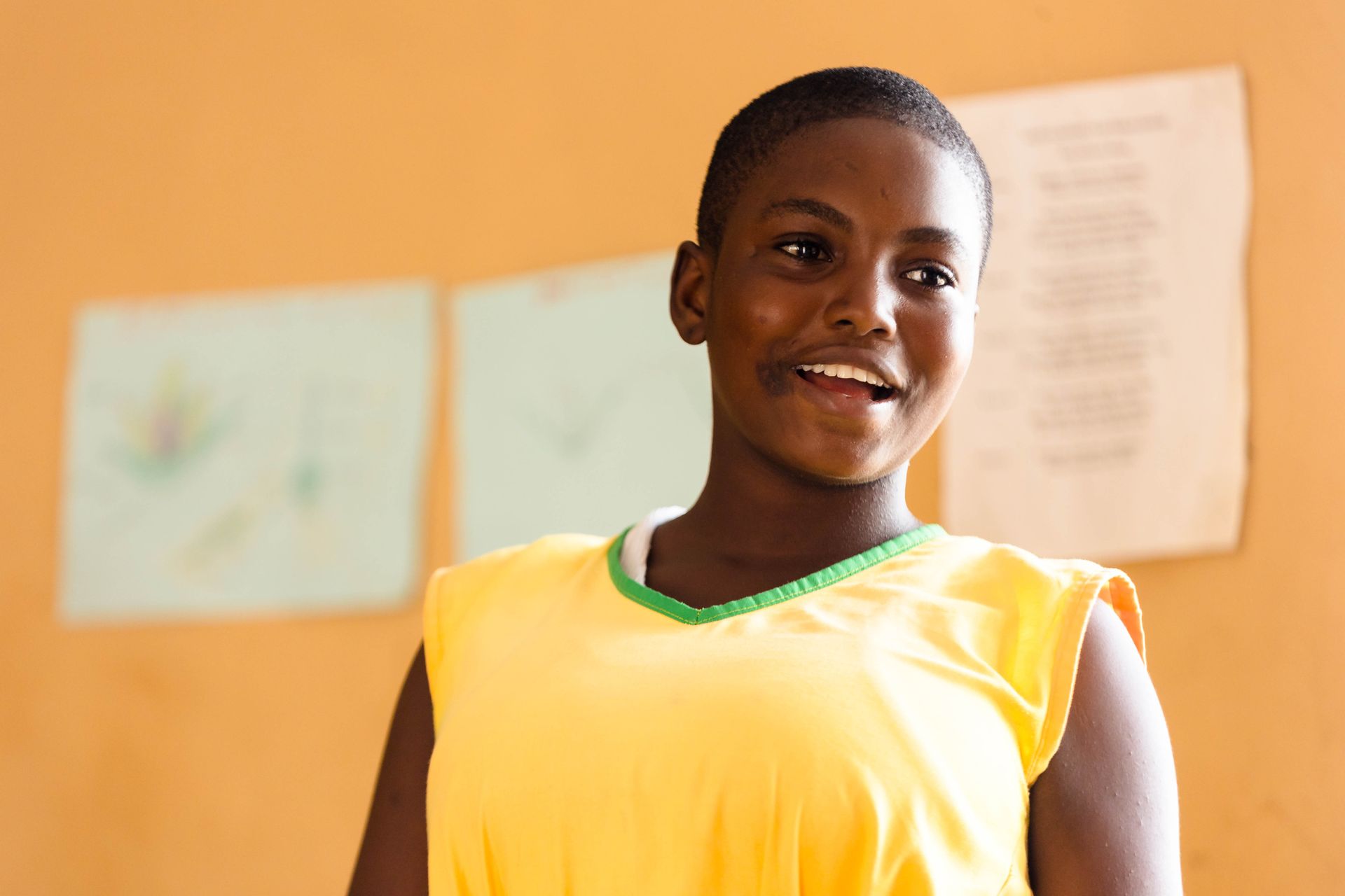 A young girl in a yellow tank top is smiling