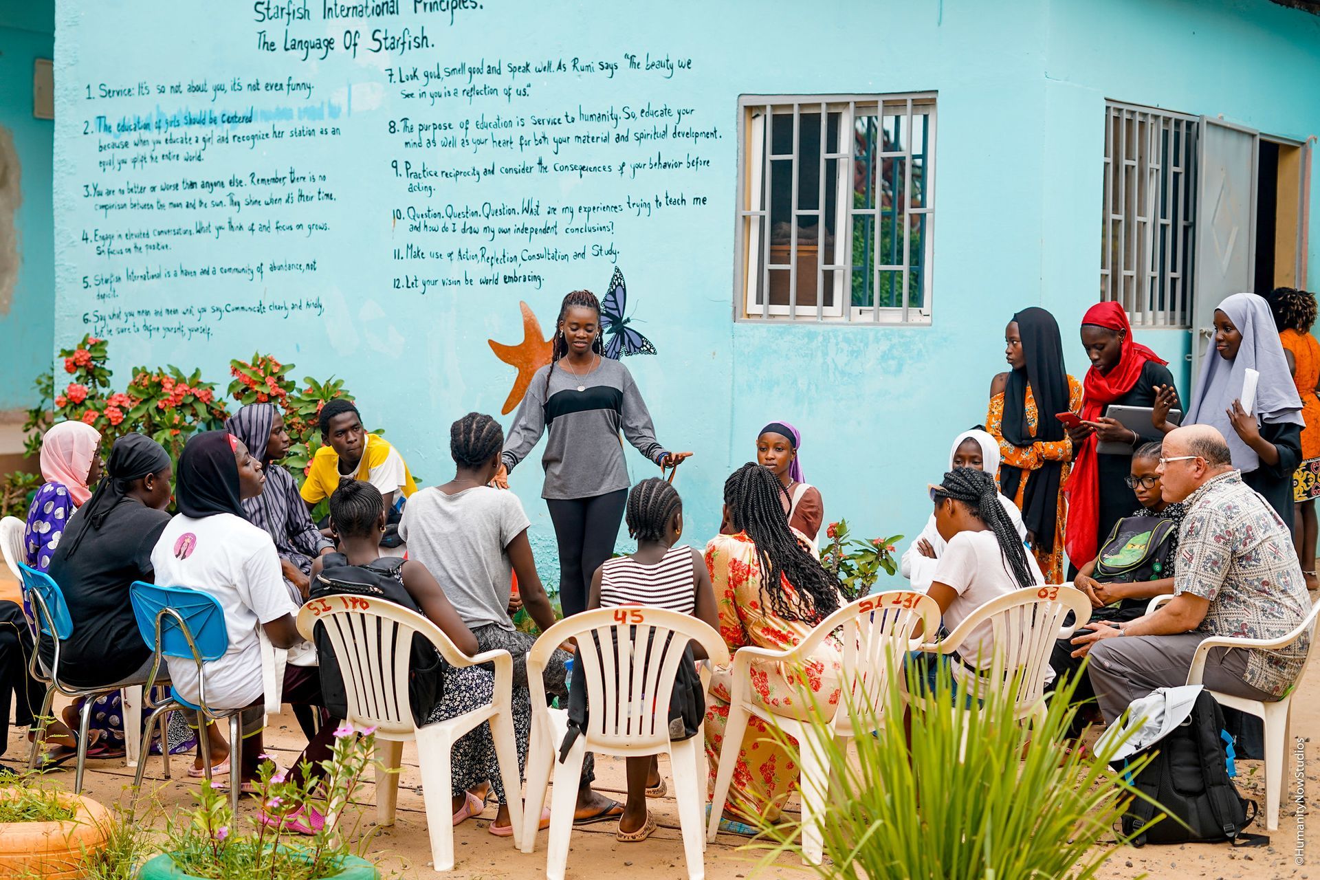 A group of people are sitting in chairs in front of a building.