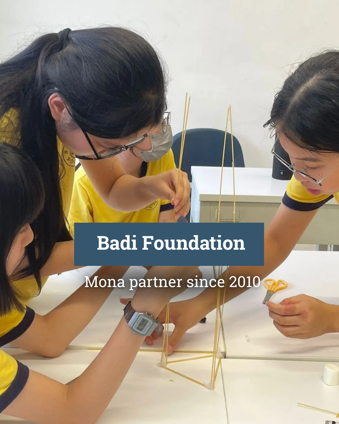 A group of young girls are sitting around a table working on a project.