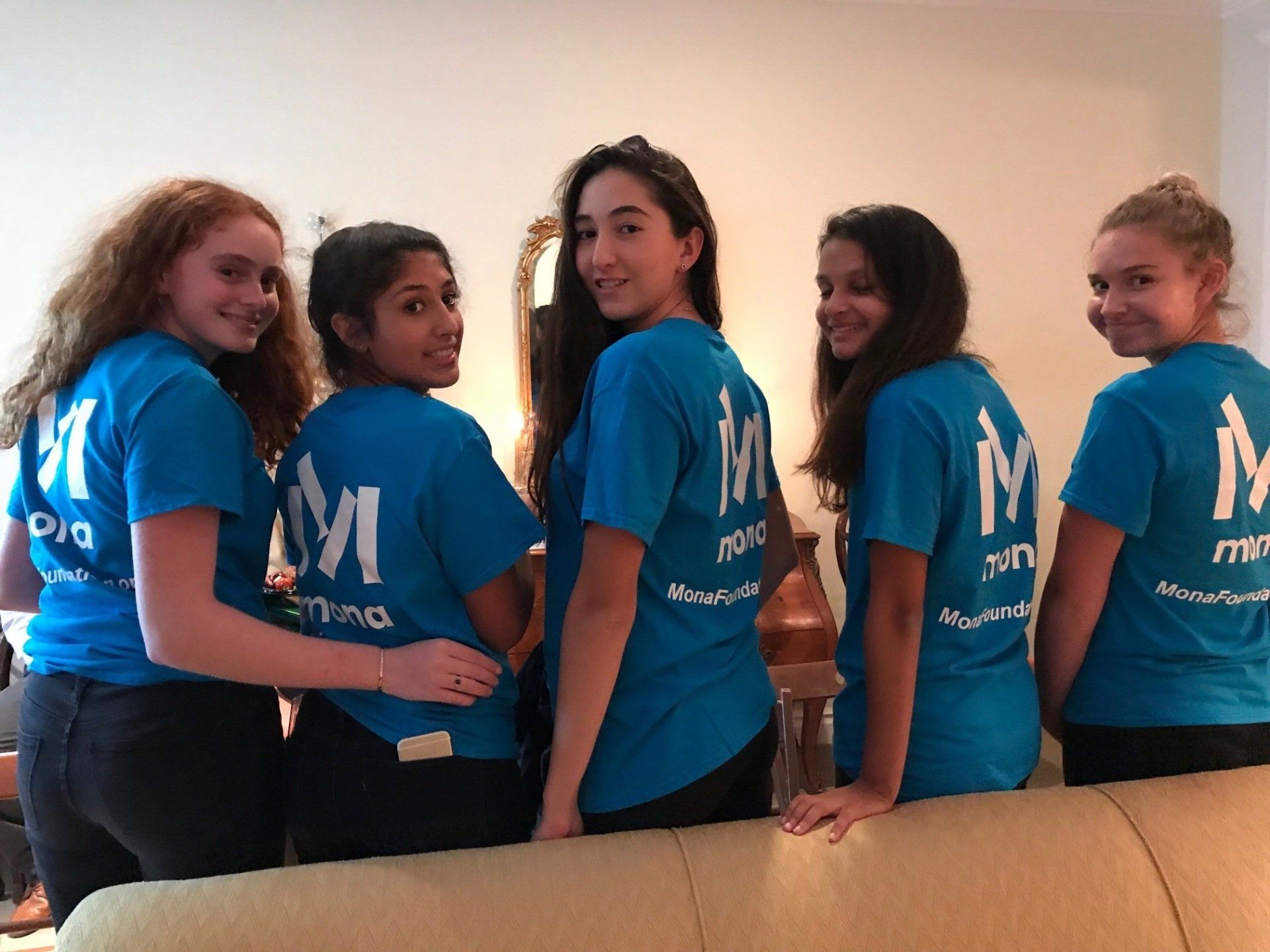 A group of girls wearing blue shirts with the letter m on the back