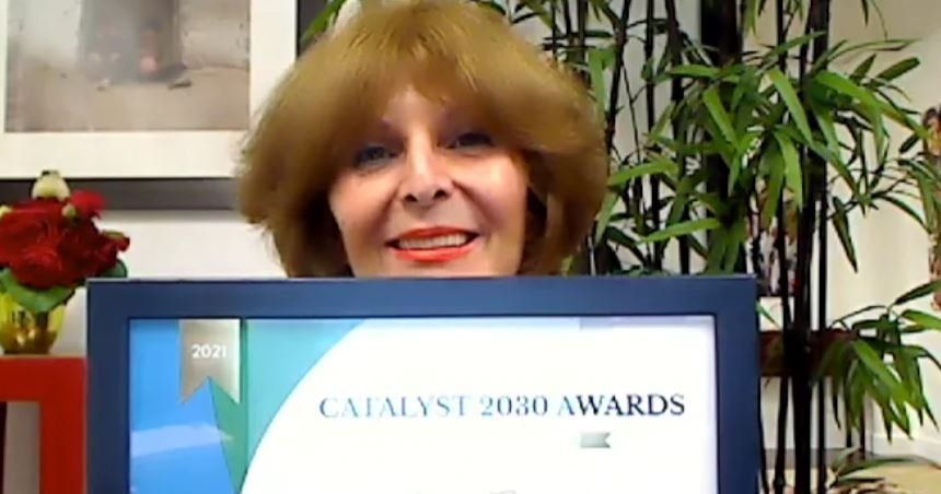 A woman is holding a certificate that says catalyst 2030 awards