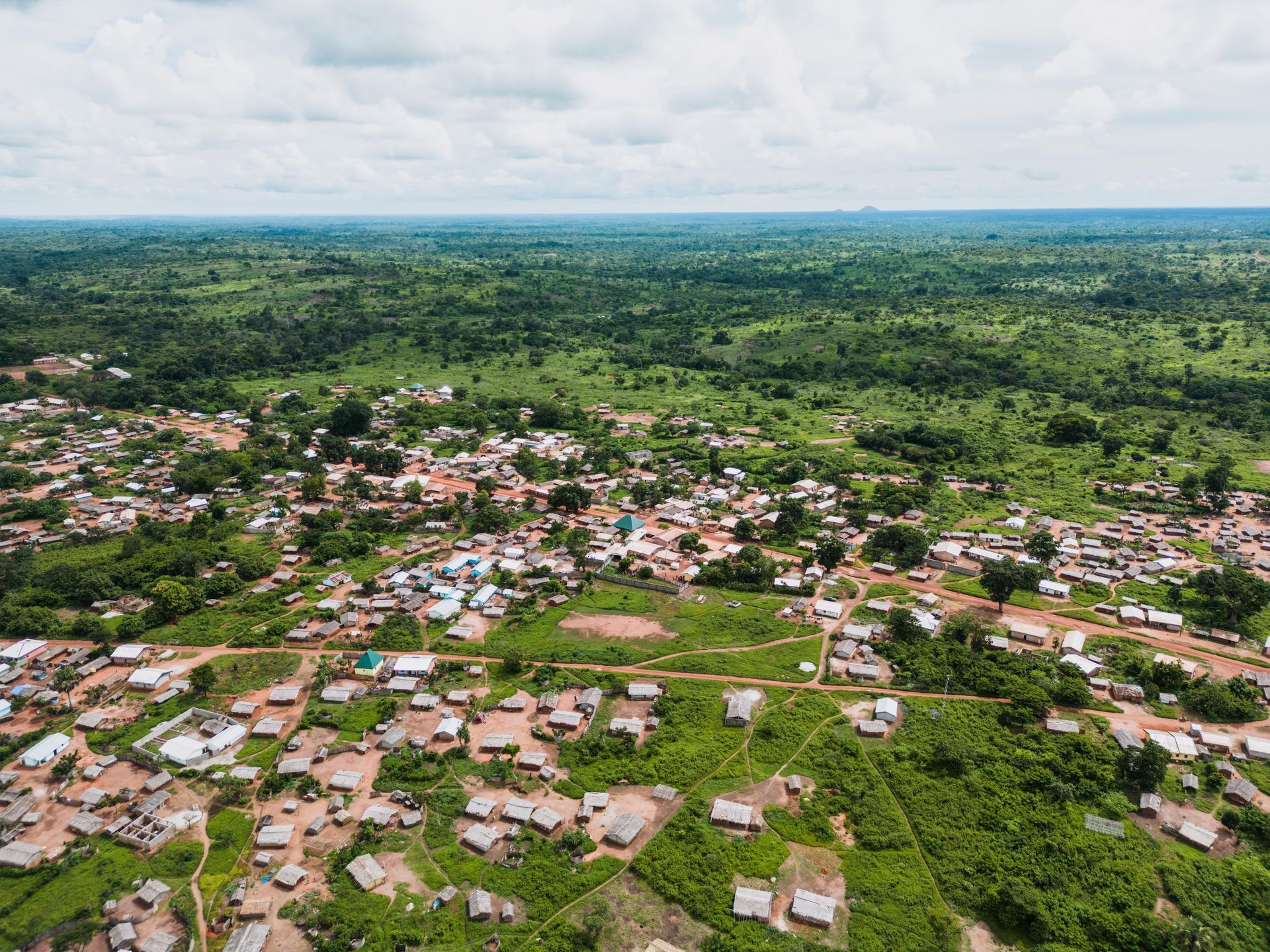 An aerial view of a small village in the middle of a lush green forest.