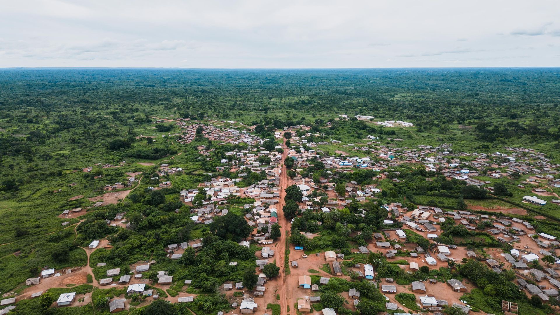 An aerial view of a small town in the middle of a lush green forest.