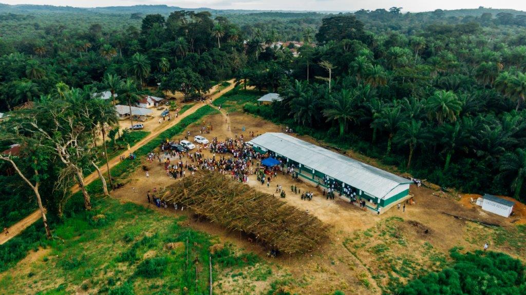 An aerial view of a large tent in the middle of a lush green forest.