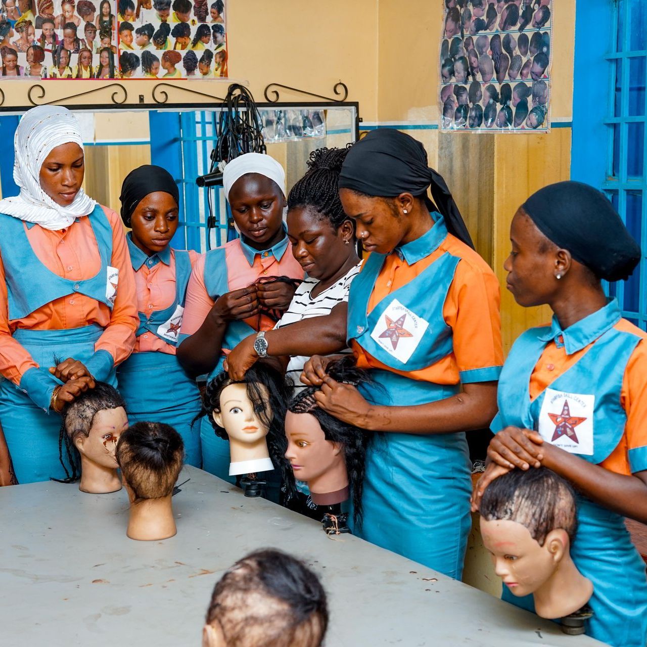 A group of women are standing around a table with mannequin heads