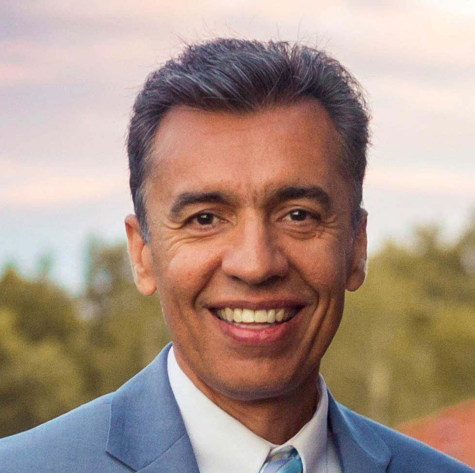 A man in a suit and tie is smiling for the camera.