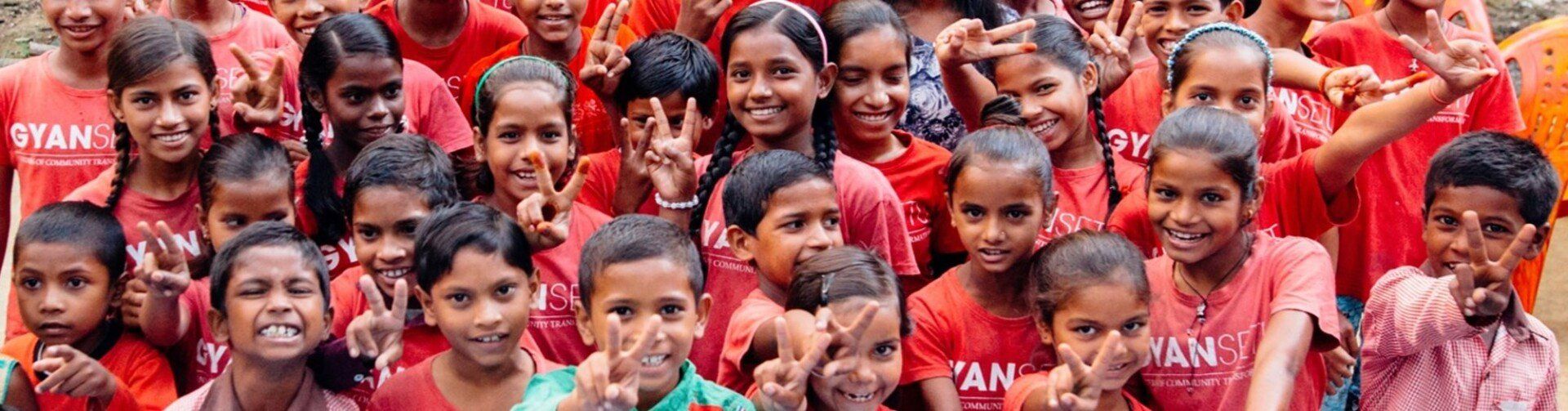 A group of children wearing red shirts are posing for a picture.