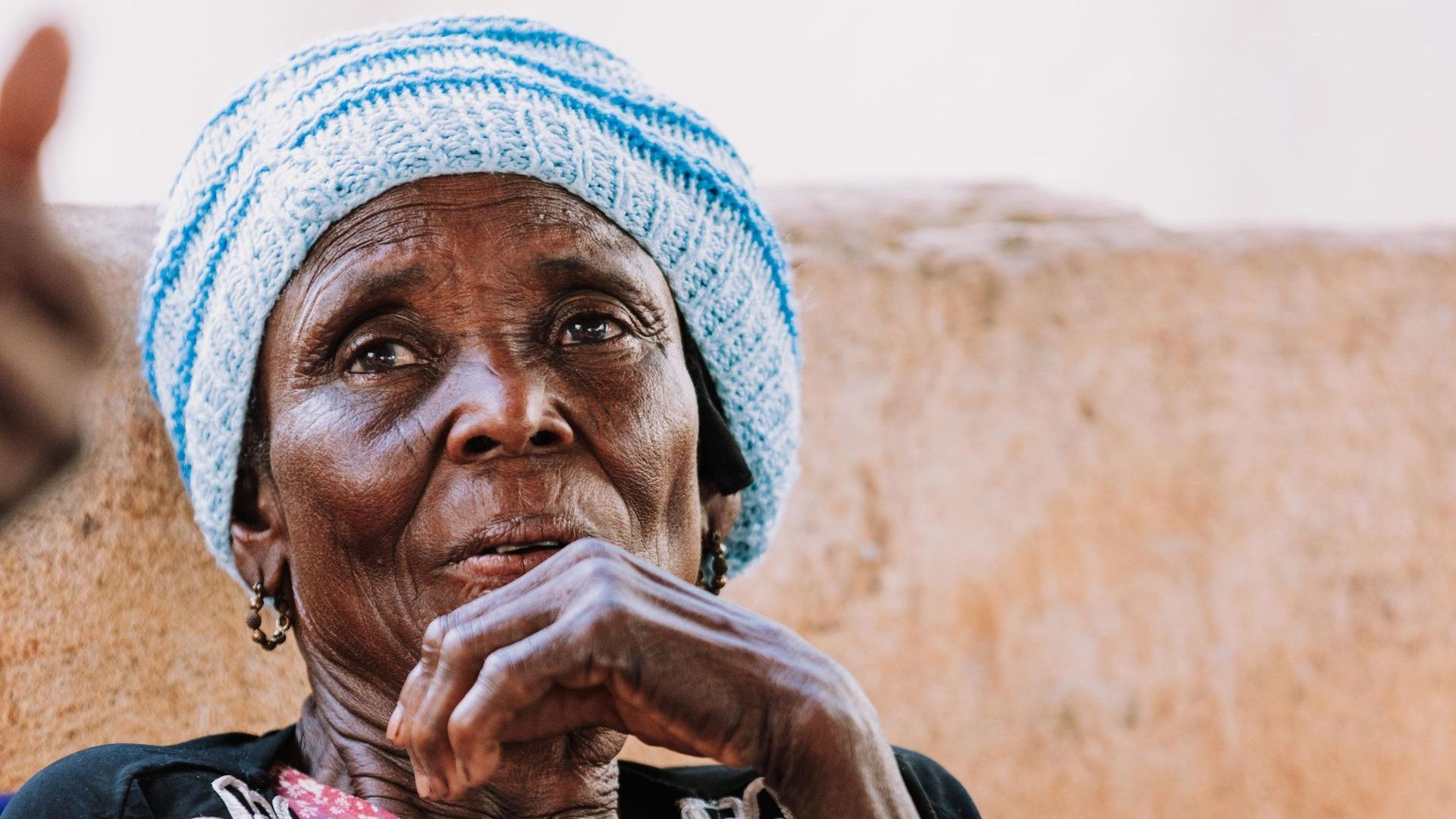 A close up of an elderly woman wearing a hat.