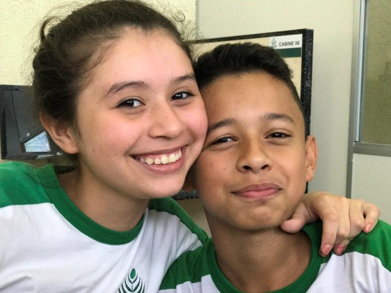 Two young students, a girl and a boy, smiling in an ADCAM t-shirt. 