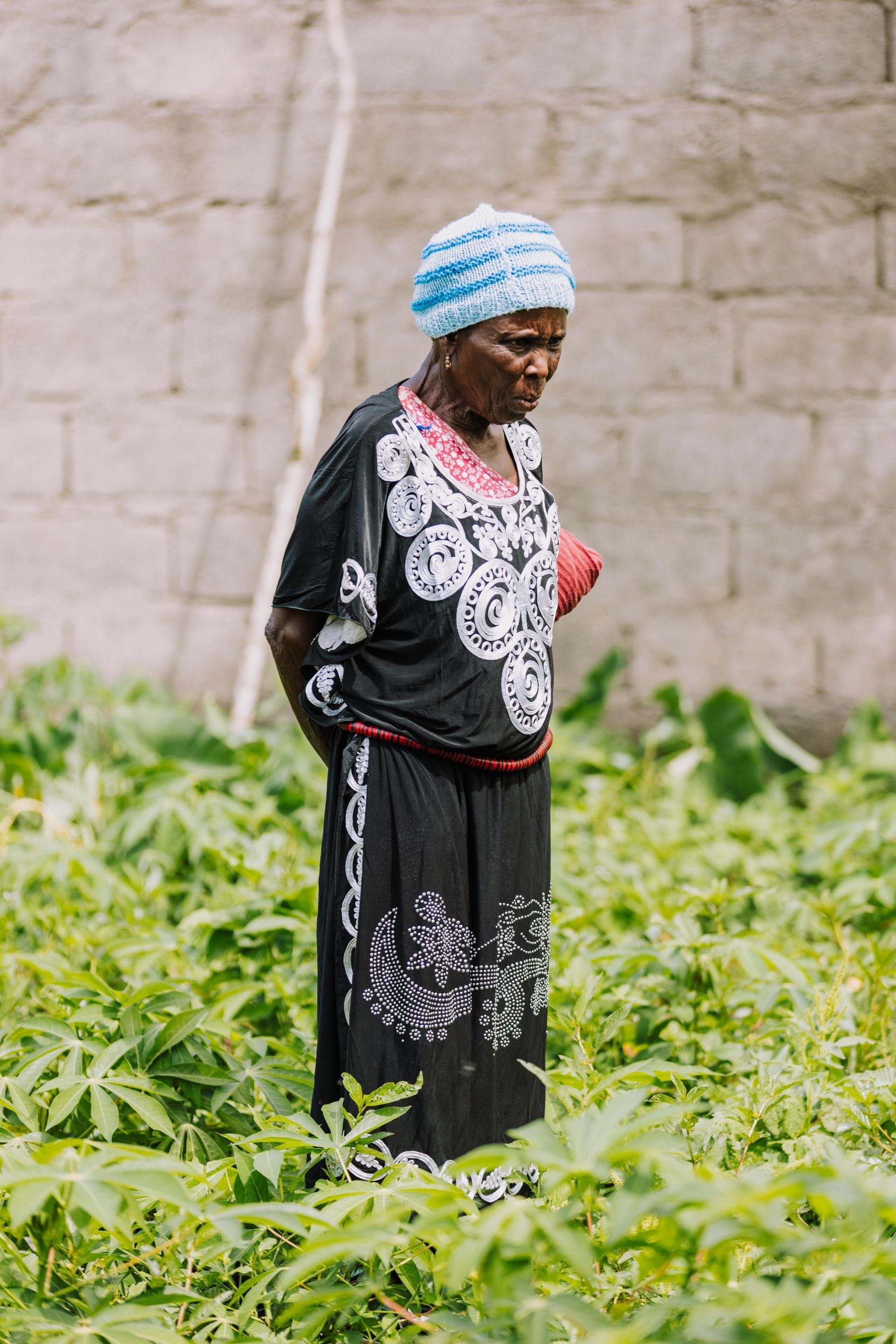 A woman is standing in a field of green plants.