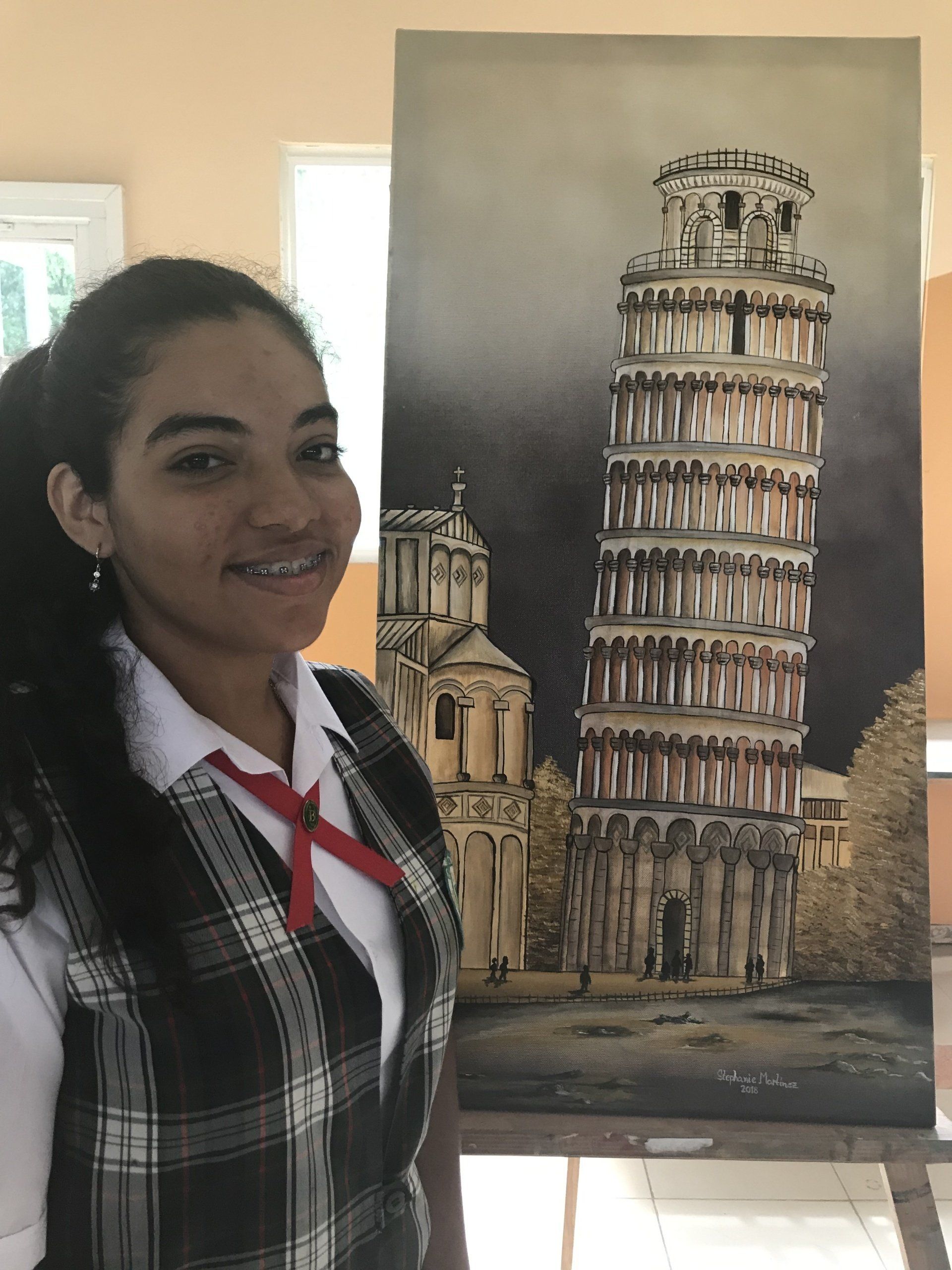 A girl is standing in front of a painting of the leaning tower of pisa