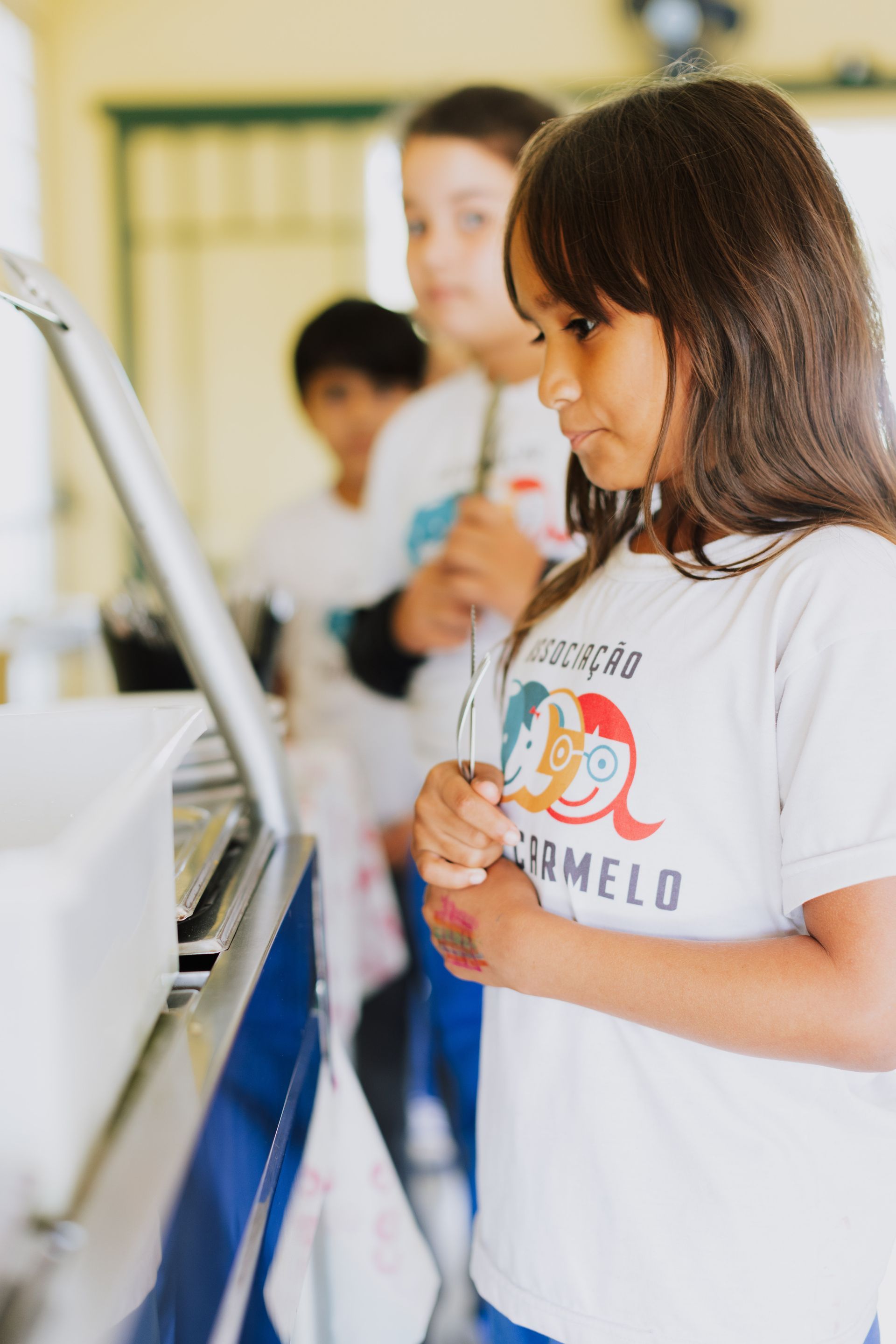 A young girl is standing in front of a counter in a school cafeteria.