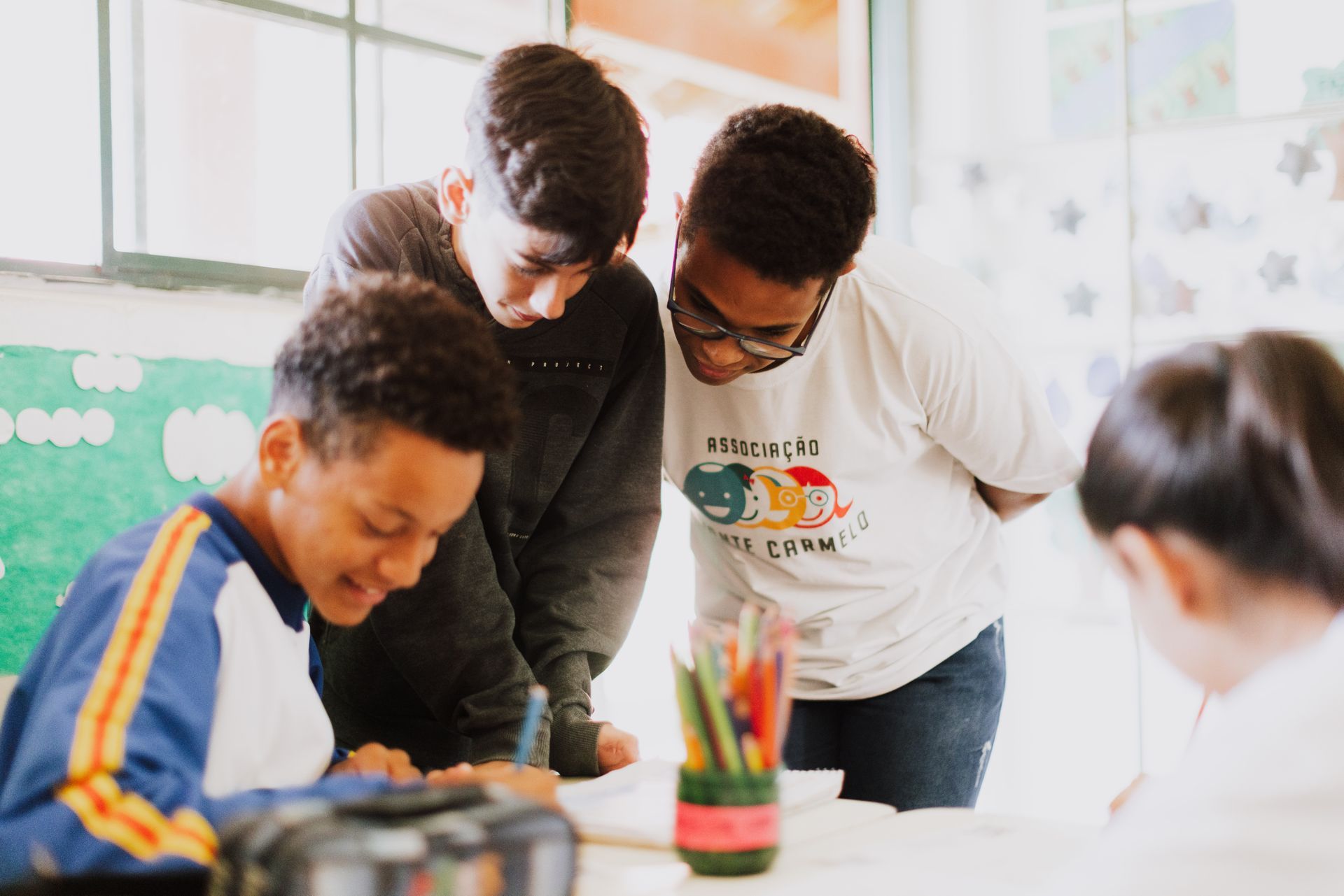 A group of young people are standing around a table in a classroom.