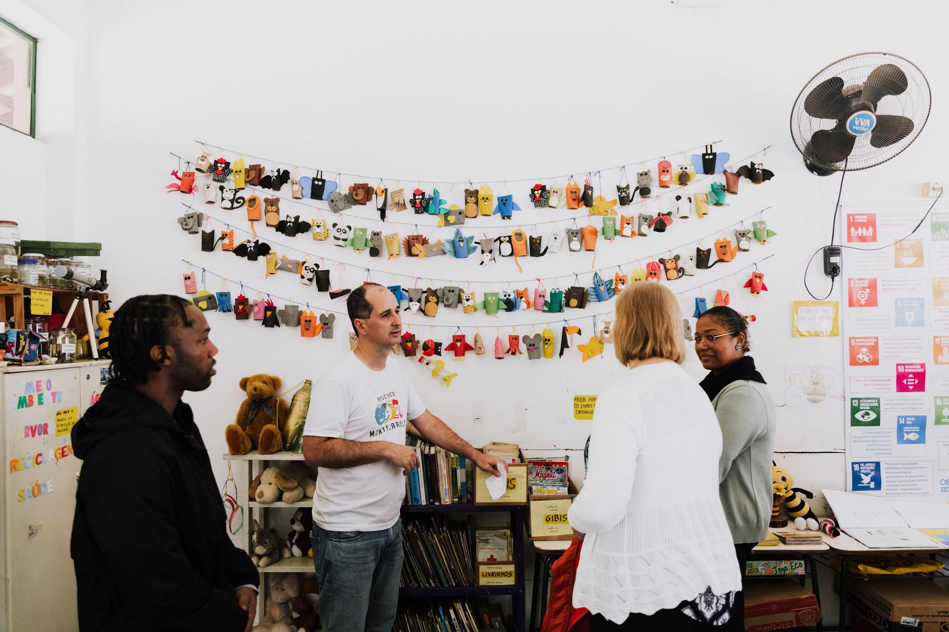 A group of people are standing in a room talking to each other.