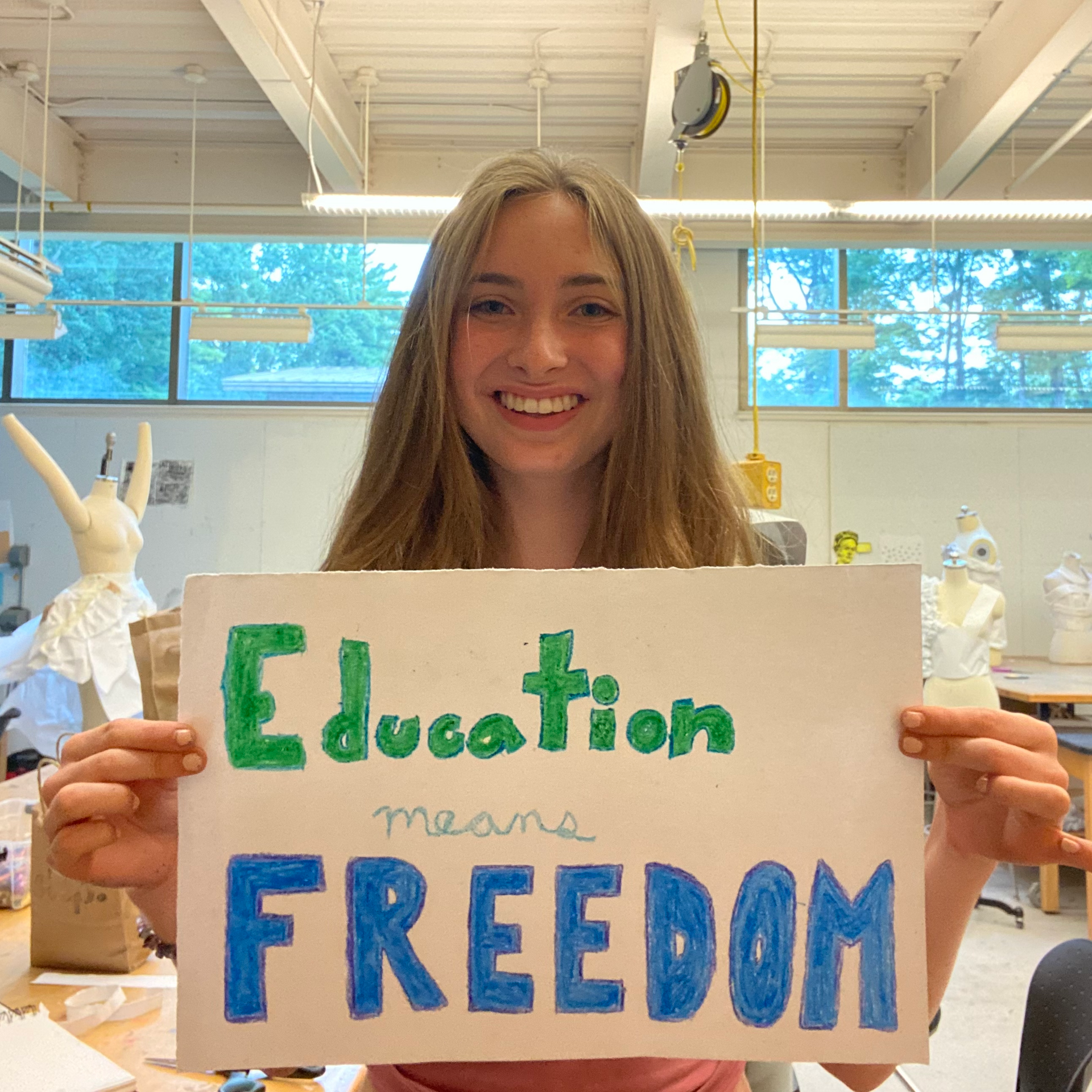 A woman is holding a sign that says education means freedom