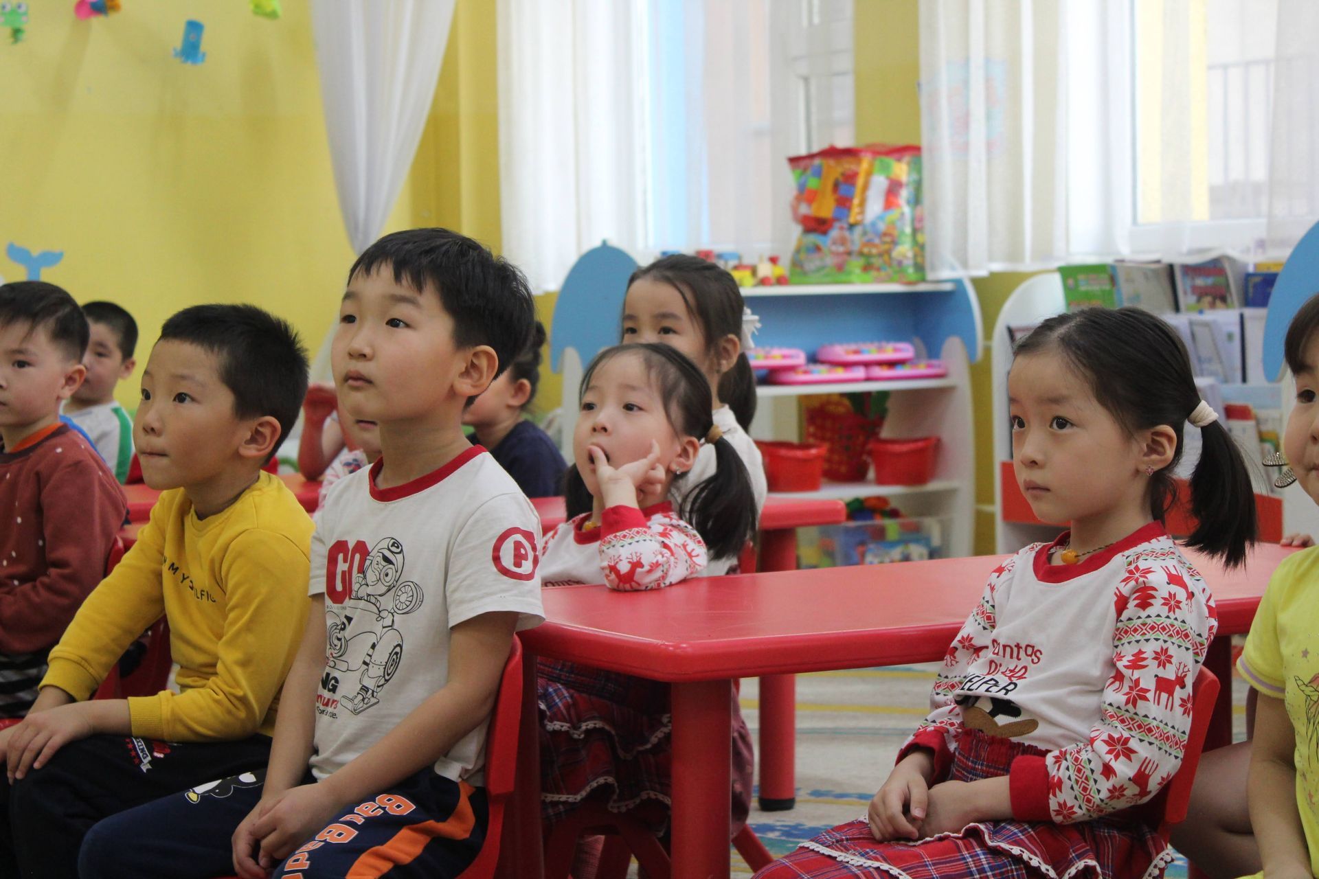 Four kindergarten students at their desks engaged and focused on their classroom. 