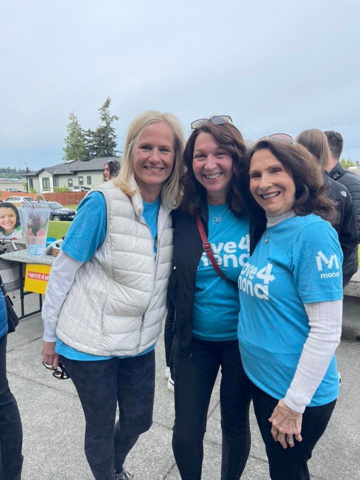 Three women wearing blue shirts and white vests are posing for a picture.