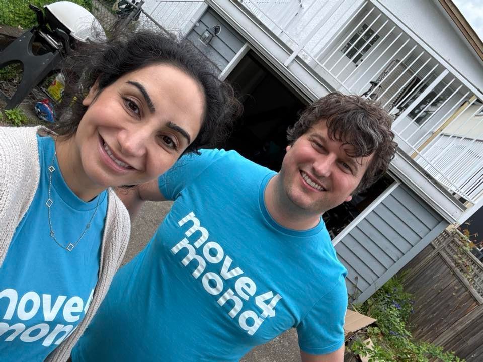 A man and a woman are posing for a picture in front of a house.