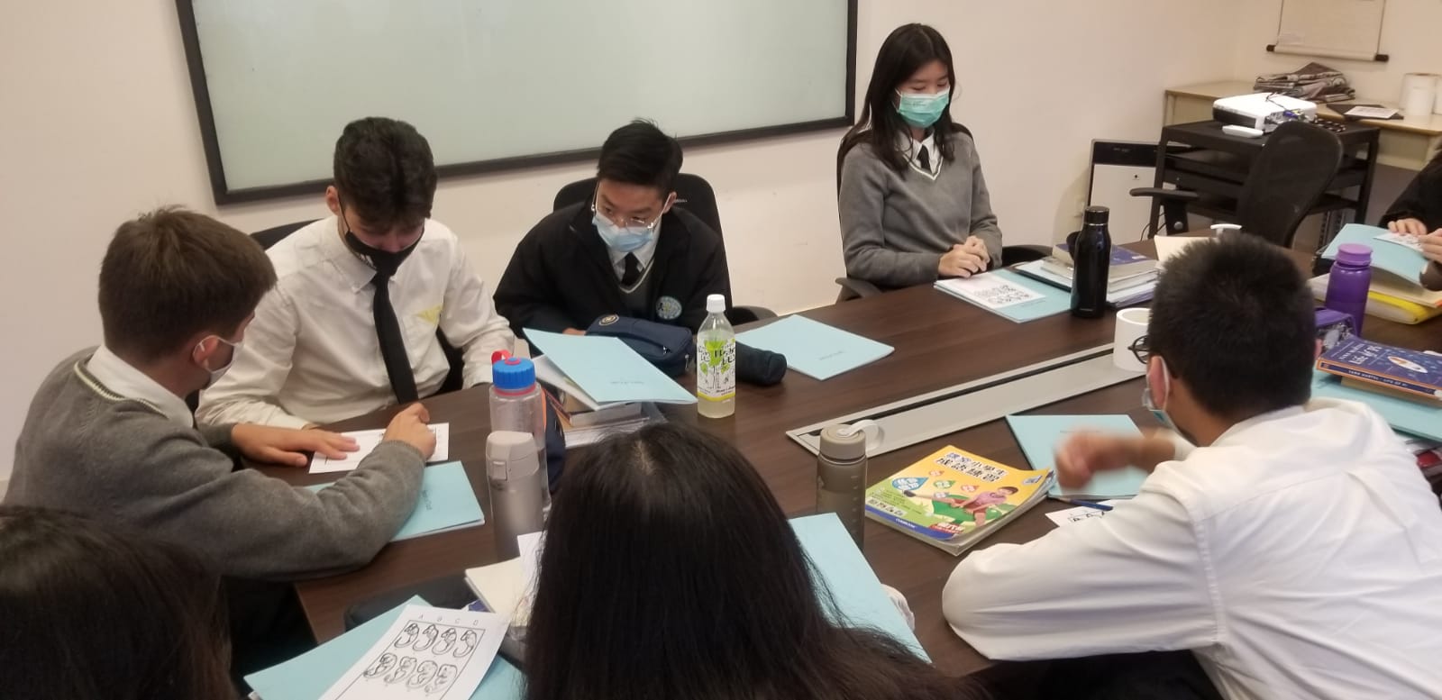 A group of students sitting at a table working on a project together. 