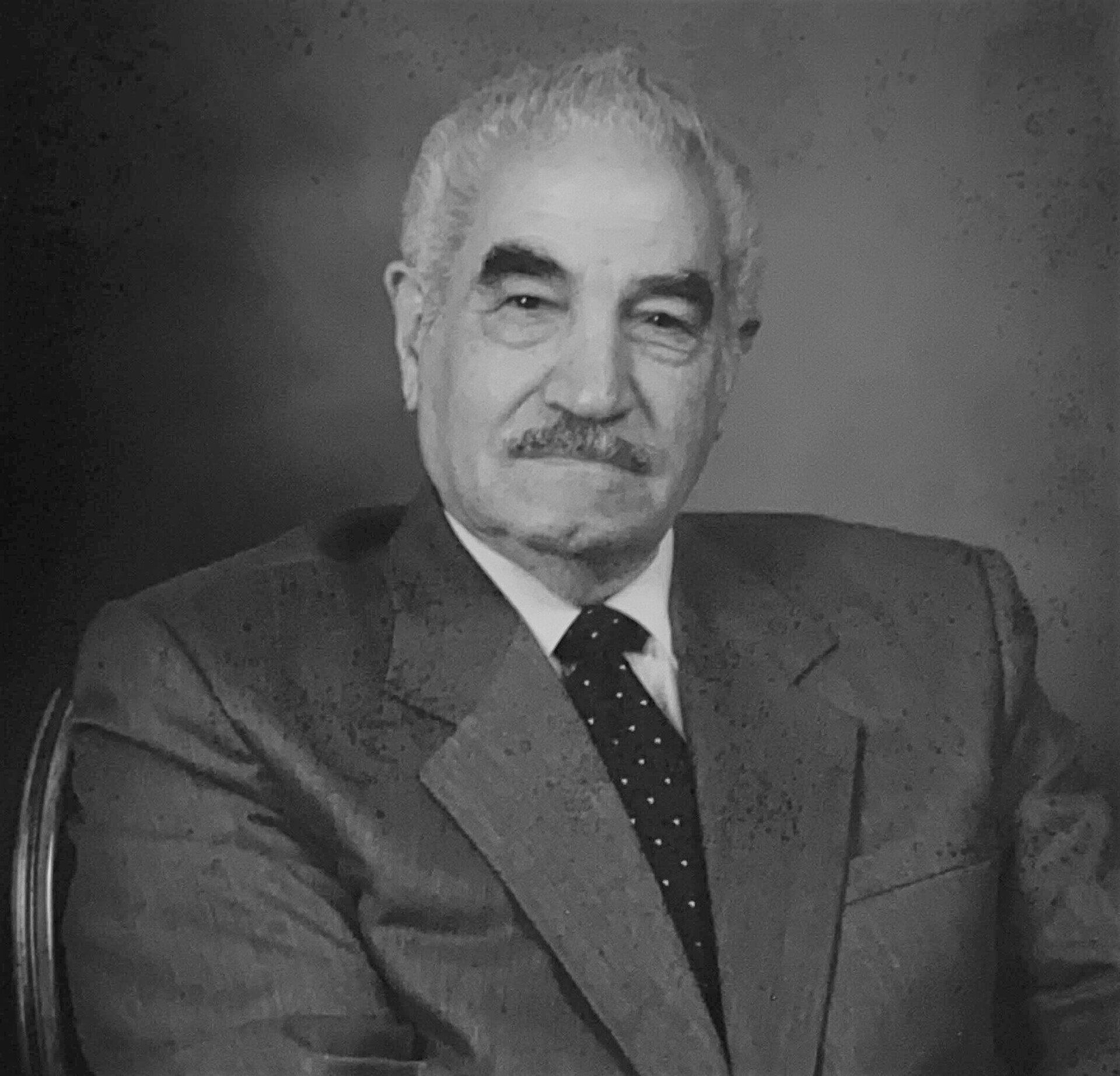 A man in a suit and tie is sitting in a chair.