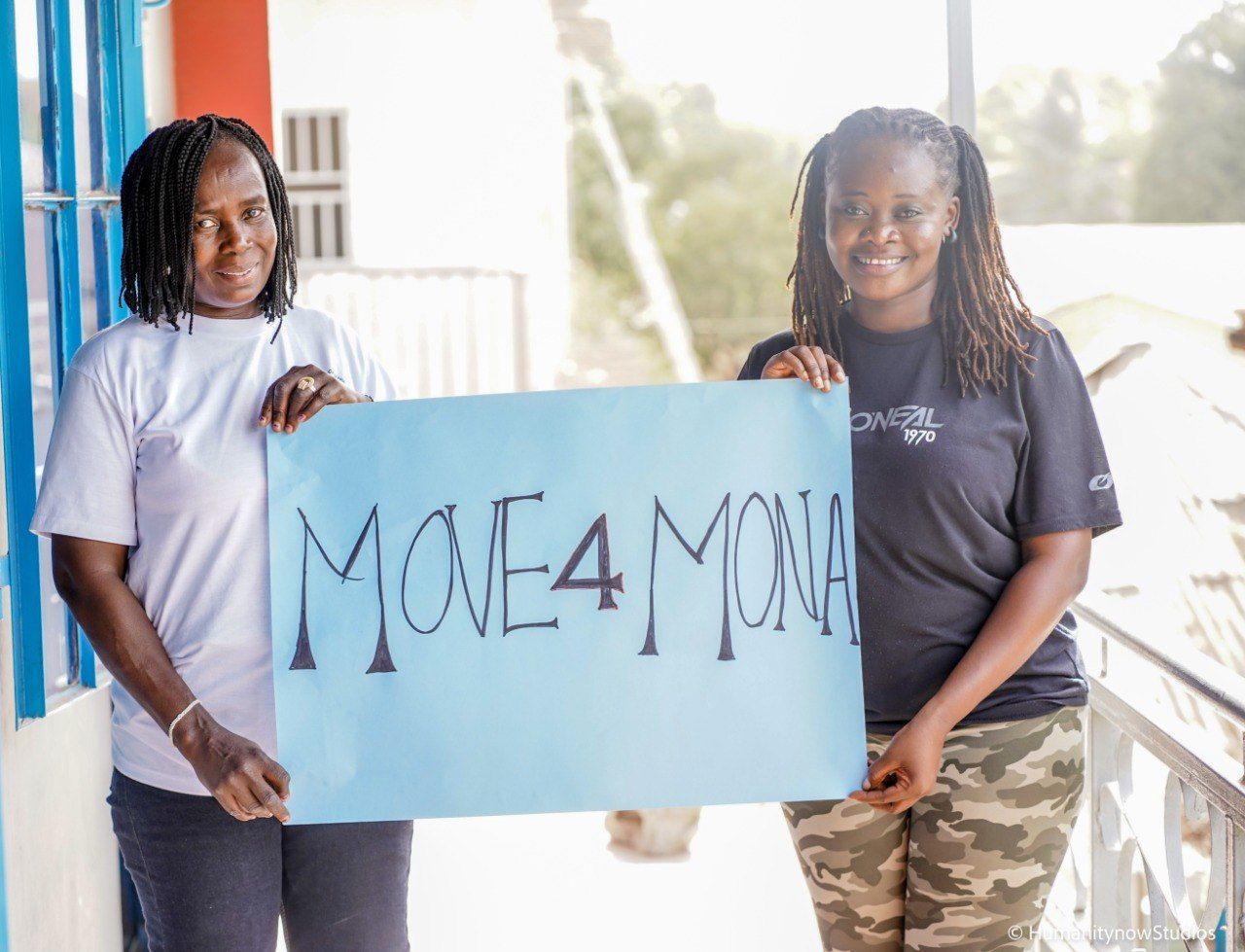 Two women are holding a sign that says move4mona