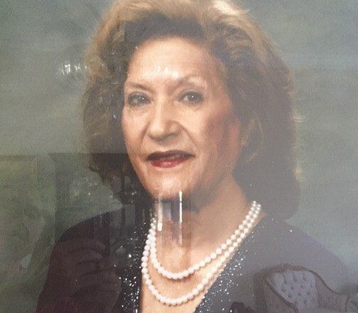 A woman is wearing a pearl necklace and a black dress.