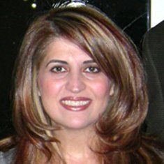 A woman with long brown hair is smiling for the camera.