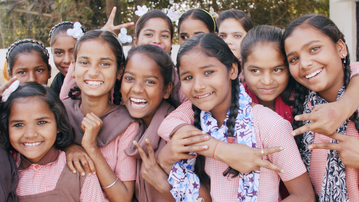 A group of young girls are posing for a picture and smiling.