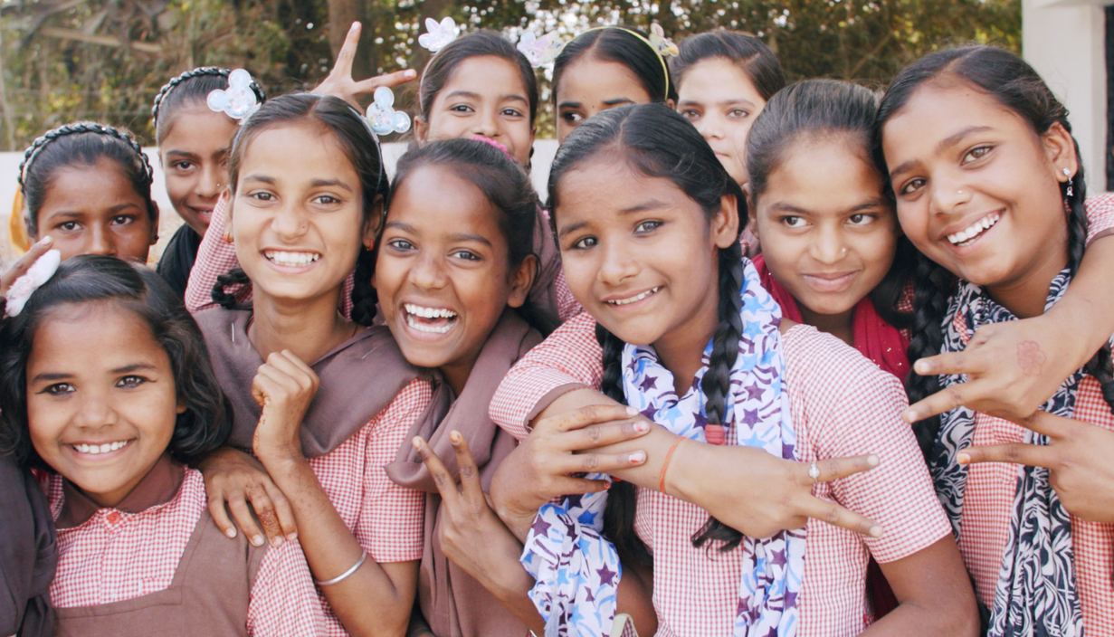 A group of young girls are posing for a picture and smiling.