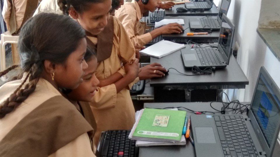 A group of children are using laptops in a computer lab
