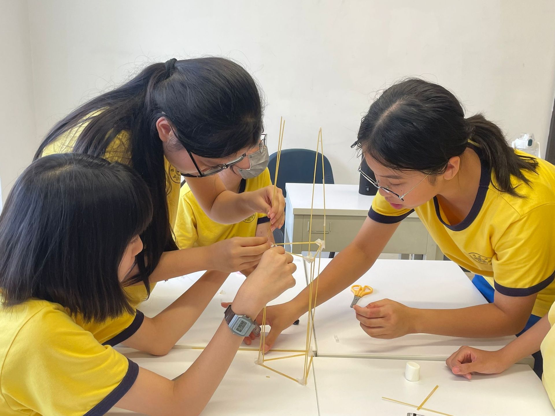 A group of young girls are sitting around a table working on a project.