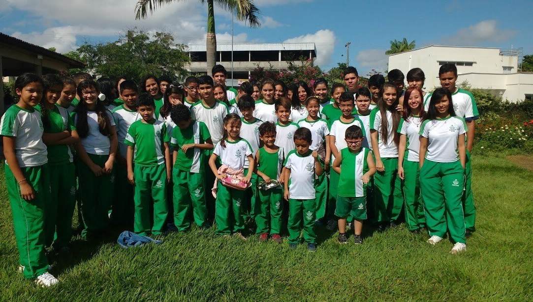 A large group of children in green uniforms are posing for a picture.