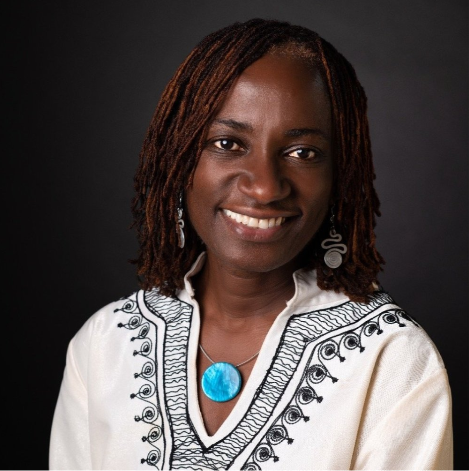 A woman wearing a white shirt and a blue necklace smiles for the camera