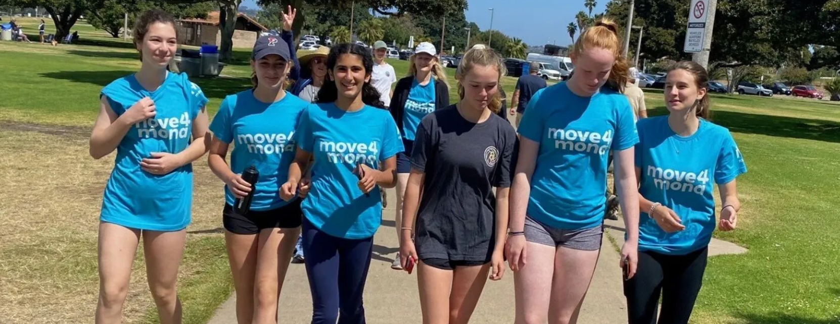 A group of young women are walking down a sidewalk in a park.