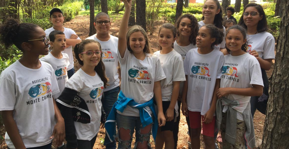 A group of young girls are posing for a picture in the woods.