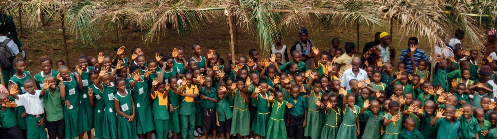 A large group of children in green uniforms are posing for a picture.
