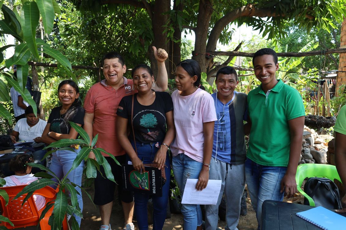 A group of people standing next to each other in front of trees.