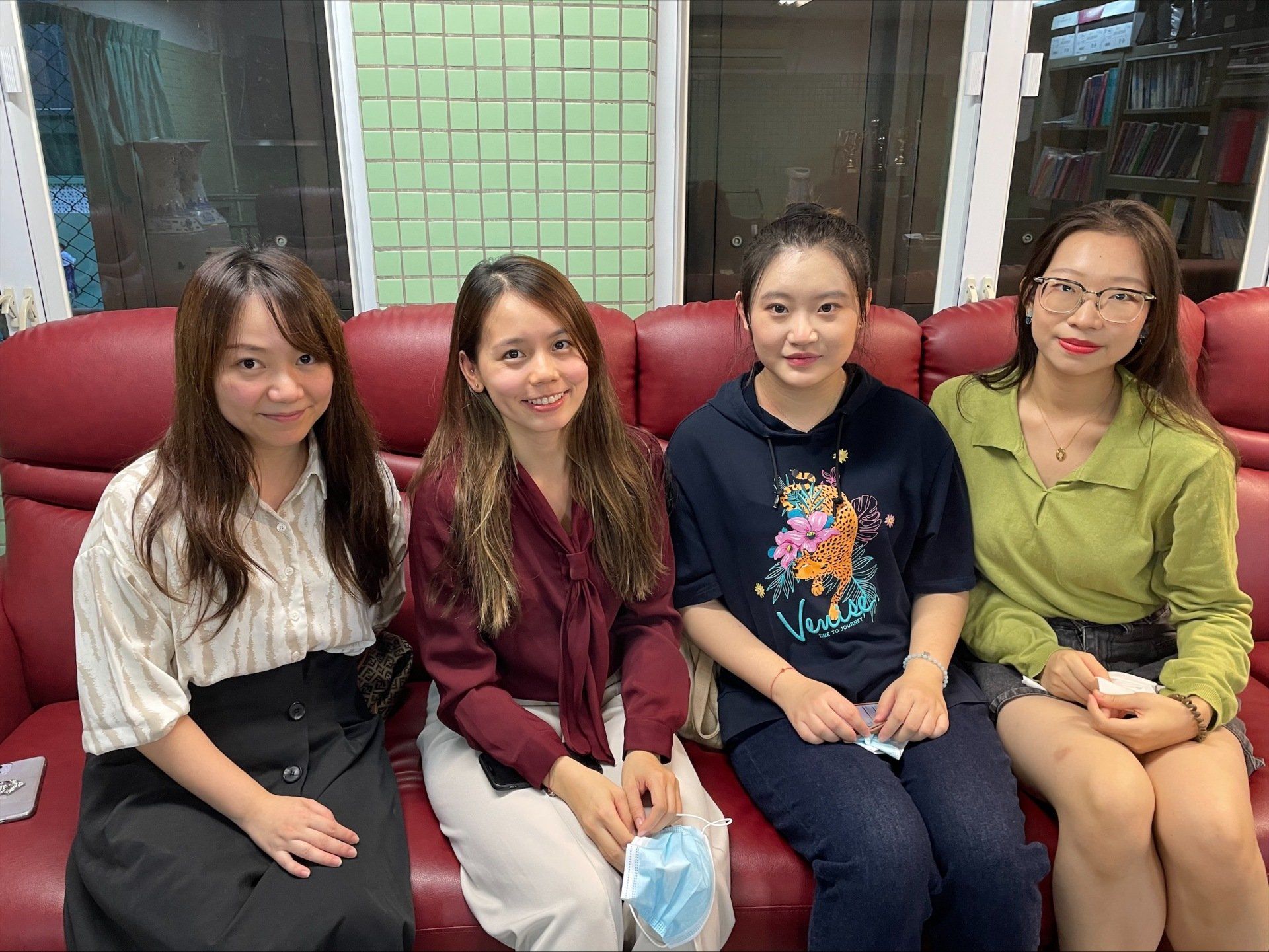 Four young girl students sitting together working on a project, all smiling and posing. 