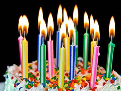 A birthday cake with lots of lit candles and sprinkles